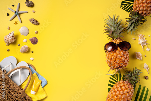 Summer fruit background design concept. Beach with shells, pineapple and palm leaves on yellow background.