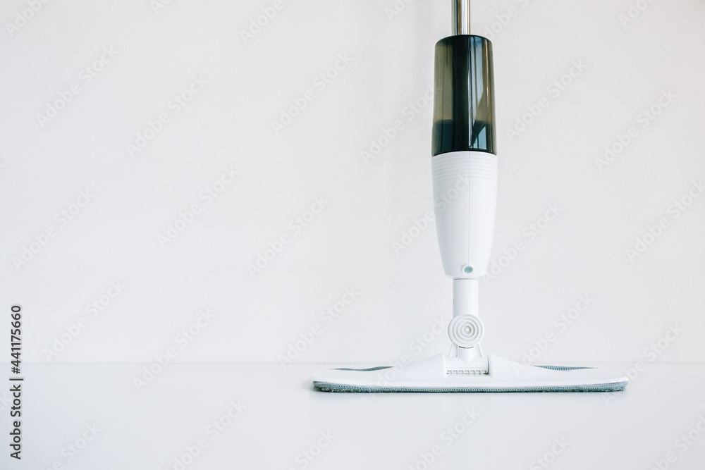 White mop with spray bottle isolated on white background with copy space. White mop with spray bottle isolated on white background with copy space.