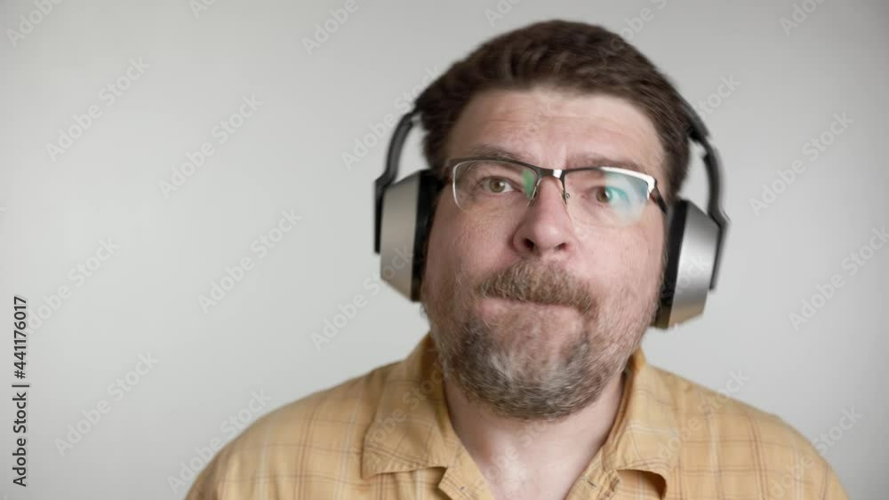 Portrait of bearded 48 years old caucasian man enjoy listen to romantic slow music by wireless silver headphones at home. Portrait of bearded 48 years old caucasian man enjoy listen to romantic slow music by wireless silver headphones at home.