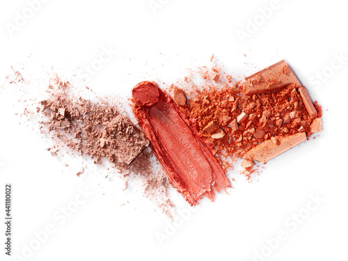 On a white background are broken blush for the face or eye shadow and smeared pink lipstick. A palette of shades. Cosmetic swatches. Decorative cosmetics on a white background. Eye makeup product.