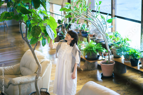 笑顔で観葉植物の様子を見る若い女性