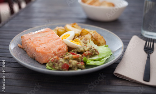 baked salmon fillet with fried potato wedges, homemade guacamole and quail eggs halves