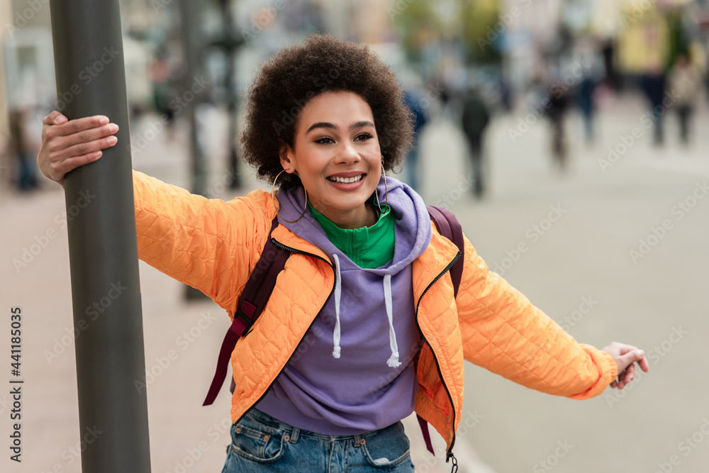 Obraz premium Cheerful african american woman standing near lantern outdoors
