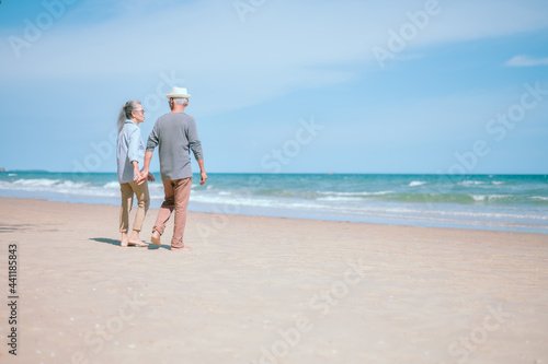 Two retired Asian couples happily run hand in hand on the beach.