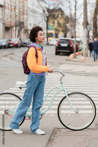 Young african american woman standing near bicycle and crosswalk outdoors