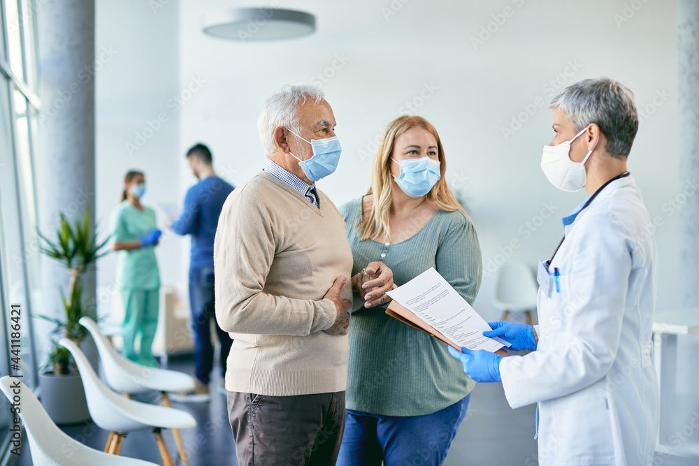 Senior man with face mask talking about his medical condition with female doctor at the hospital. Senior man with face mask talking about his medical condition with female doctor at the hospital.