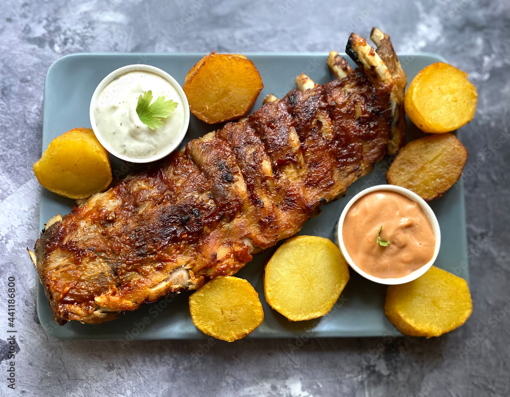 Grilled barbecue pork rib with fried potatoes, american sauce and garlic sauce. Grilled barbecue pork rib with fried potatoes, american sauce and garlic sauce.