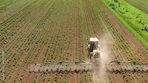 Tractor with pesticide fungicide insecticide sprayer on farm land, top view. Spraying with pesticides and herbicides crops. photo