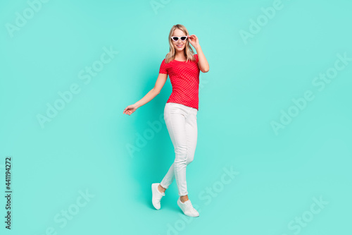 Full length body size photo woman walking wearing stylish sunglass summer isolated bright teal color background © deagreez