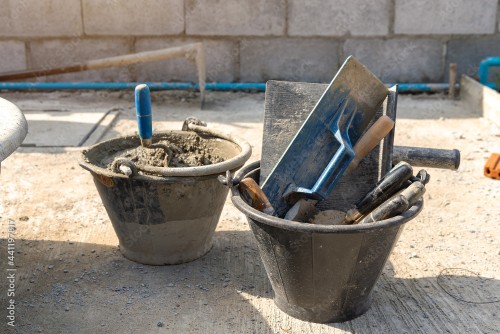 Dirty trowel and bucket with mortar at construction site Dirty trowel and bucket with mortar at construction site