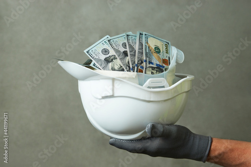 Construction worker with a hard hat full of dollar money photo