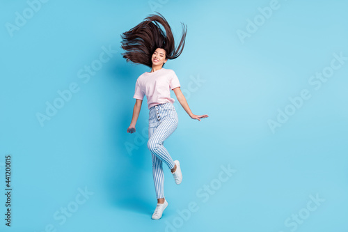 Full length body size view of attractive cheerful girl jumping having fun good mood isolated over bright blue color background