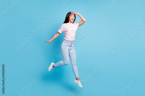 Full length body size view of attractive cheerful ecstatic thin girl jumping searching way isolated over bright blue color background