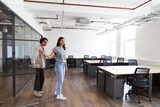 Young couple looking at work space for start up business to rent walking into open plan office