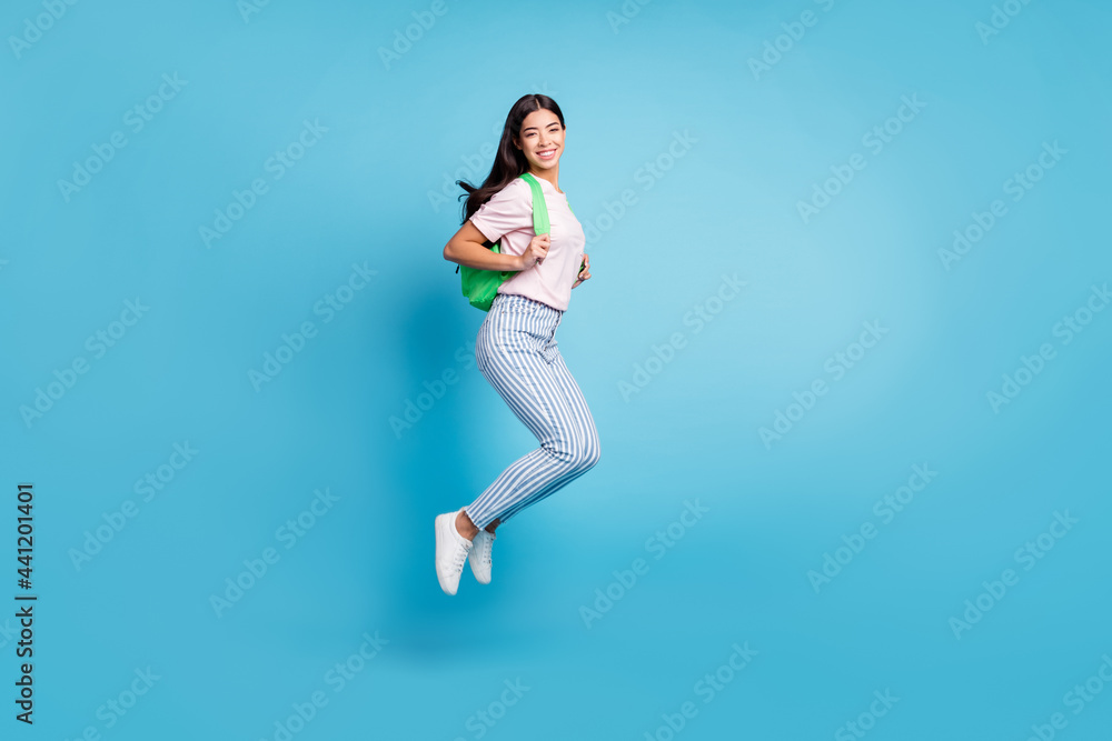 Full body profile side photo of happy nice young woman wear backpack smile jump isolated on blue color background