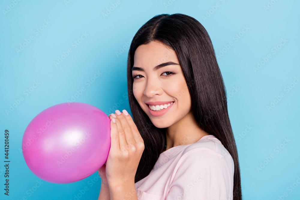 Profile side photo of young asian girl happy positive smile blow air balloon decoration isolated over blue color background Profile side photo of young asian girl happy positive smile blow air balloon decoration isolated over blue color background