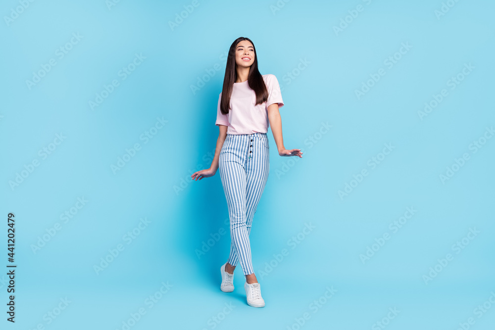 Full size photo of young attractive girl happy positive smile look empty space go walk isolated over blue color background
