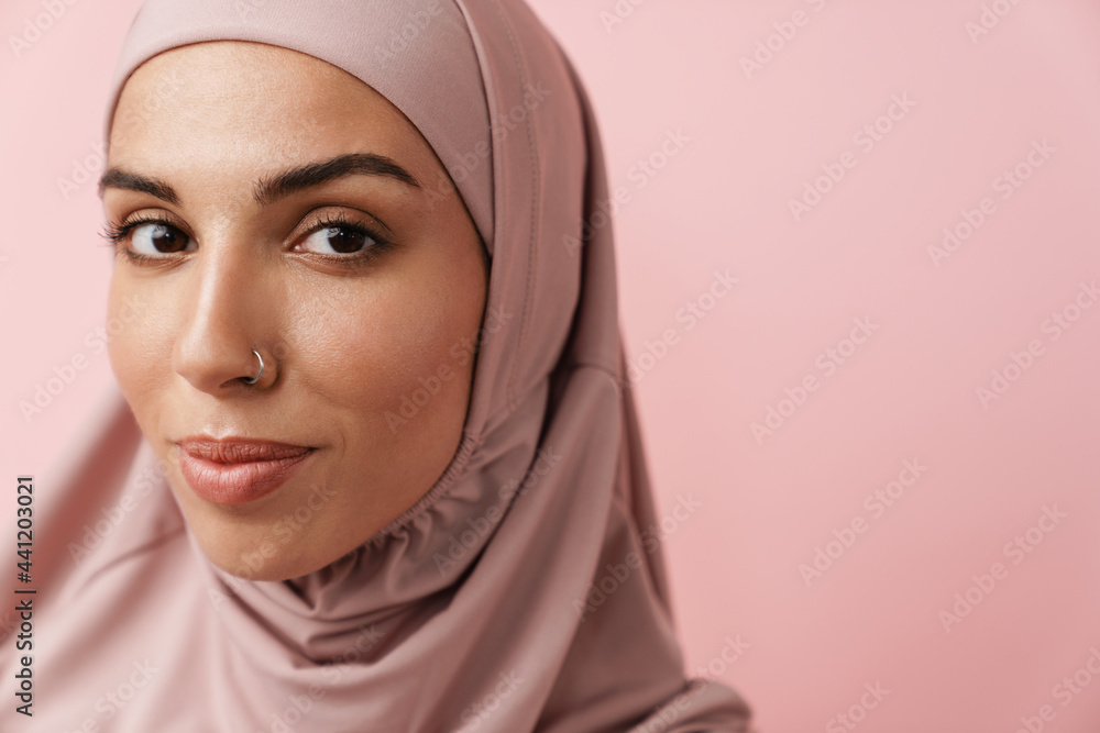 A close-up view of the positive muslim woman in pink hijab looking at the camera A close-up view of the positive muslim woman in pink hijab looking at the camera