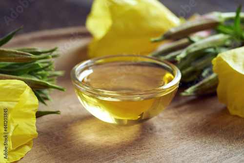 A bowl of evening primrose oil with fresh evening primrose flowers. Alternative medicine.