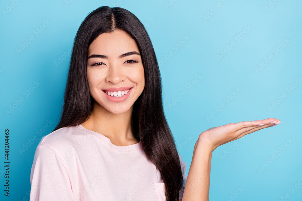 Portrait of attractive cheerful confident girl holding on palm copy space ad advert isolated over bright blue color background Portrait of attractive cheerful confident girl holding on palm copy space ad advert isolated over bright blue color background