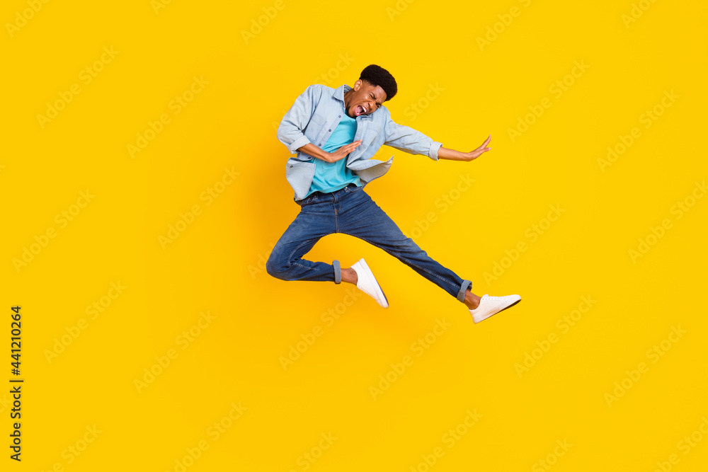 Photo of cool funny dark skin guy dressed denim shirt practicing karate jumping high isolated yellow color background