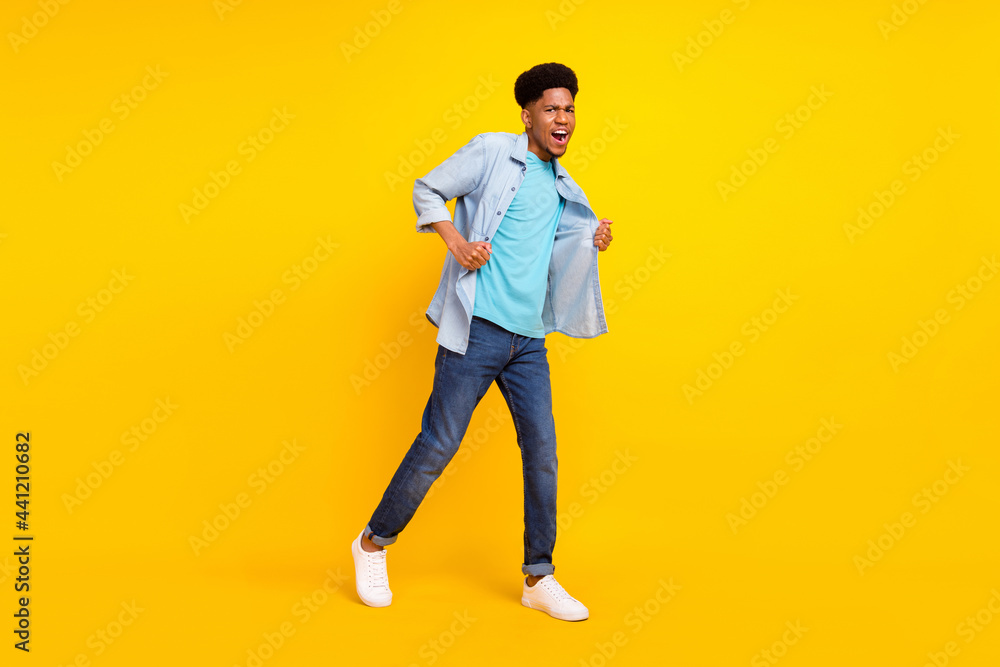 Photo of funny cool dark skin guy dressed denim shirt walking dancing singing isolated yellow color background Photo of funny cool dark skin guy dressed denim shirt walking dancing singing isolated yellow color background