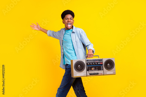 Photo of cute funky dark skin man wear jeans shirt listening boombox singing dancing isolated yellow color background