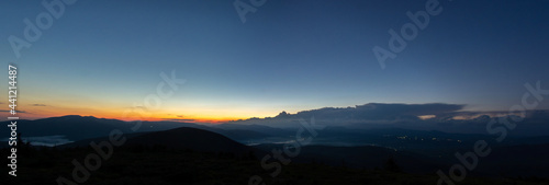 Fototapeta Naklejka Na Ścianę i Meble -  Panorama of the Carpathian mountains at sunset and the lights of the village in the haze, rest and travel in the mountains