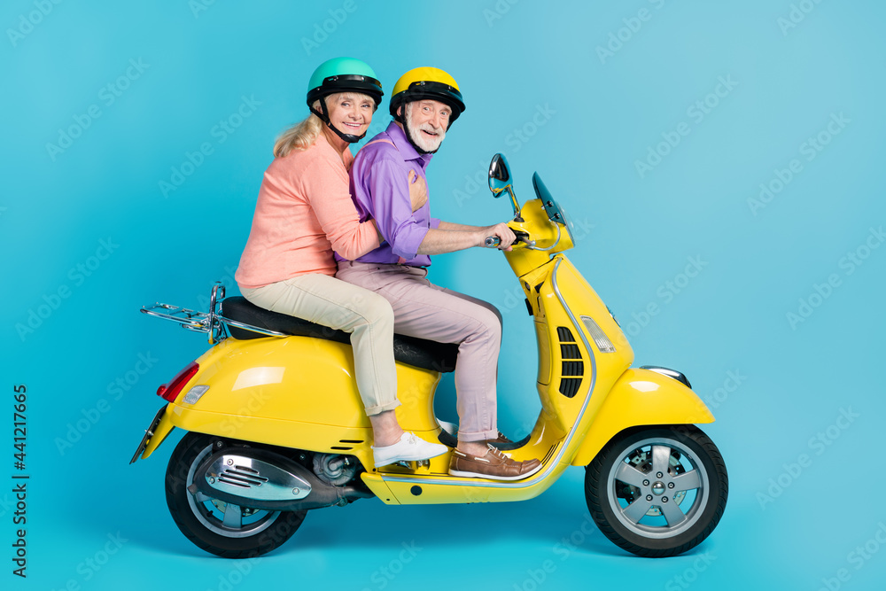 Photo of funny pretty grandmother grandfather motorcyclist wear helmets smiling isolated blue color background Photo of funny pretty grandmother grandfather motorcyclist wear helmets smiling isolated blue color background