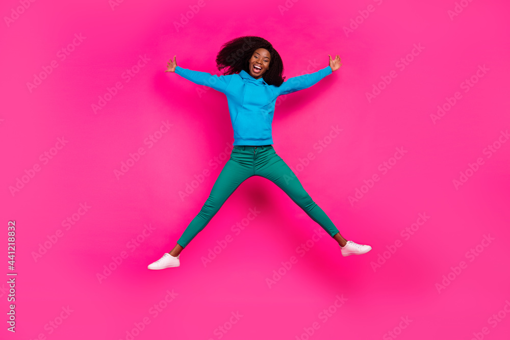 Fototapeta premium Photo of pretty funny dark skin woman dressed blue sweatshirt smiling jumping high like star isolated pink color background