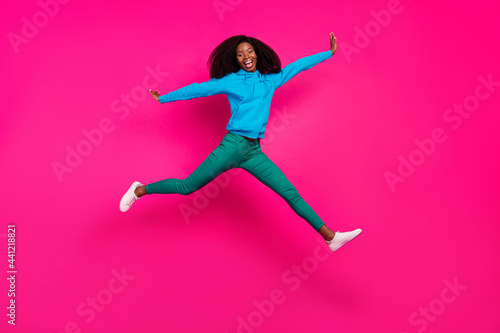 Full length body size photo of girl in stylish outfit jumping up laughing isolated vibrant pink color background