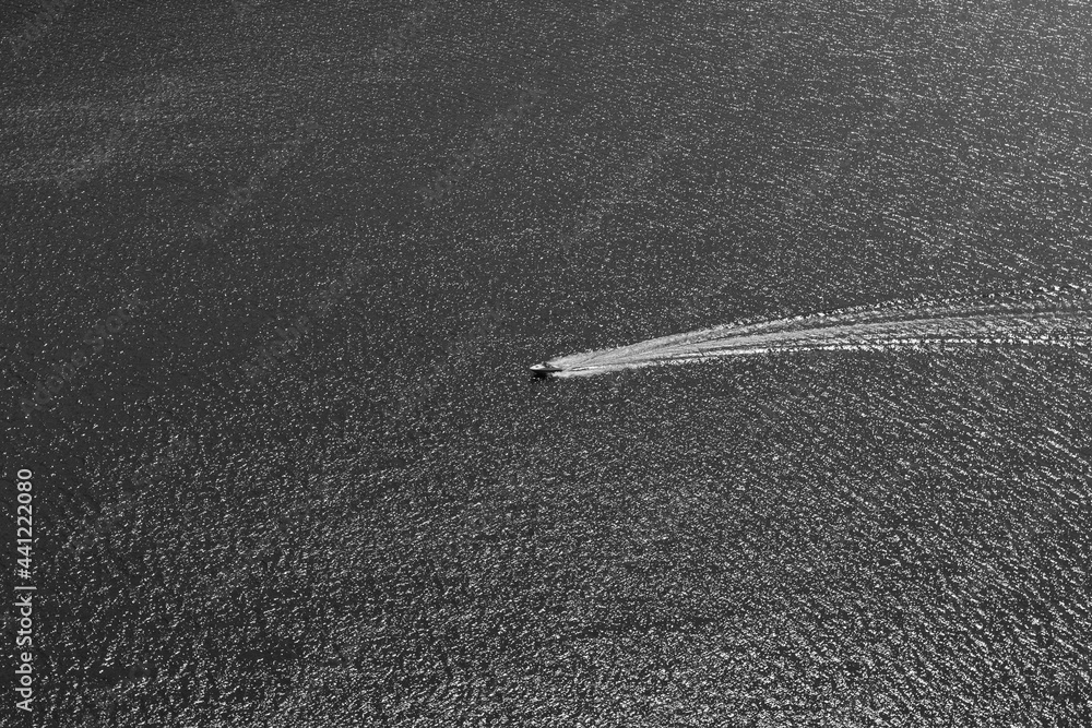 Boat on lake cruising over rippled water minimalist black and white view.
