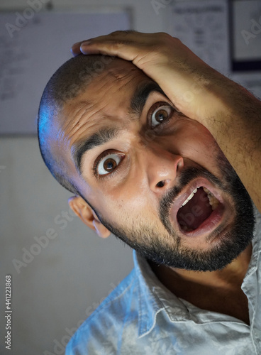 A bald young man shocked in front of camera