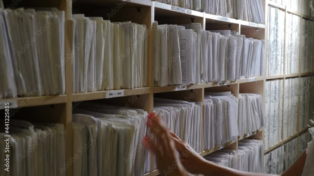 Female hands sorting folders in drawer for papers. Medical Archive and Search for Medical Documents. Paper files with notes in clinic. Old fashioned traditional medical cards on shelves in hospital. 4