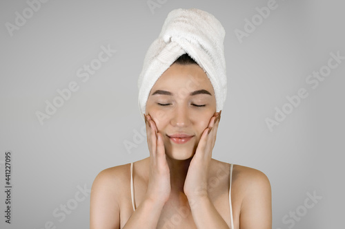 Washing your face. Closeup of woman cleaning skin with towel portrait. The woman touches her skin with her hands and smiles. High quality studio shot. 