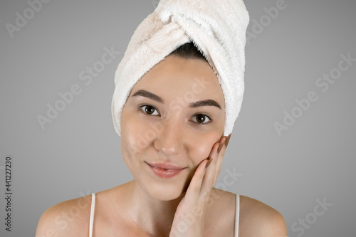 Washing your face. Closeup of woman cleaning skin with towel portrait. The woman touches her skin with her hands and smiles. High quality studio shot. 