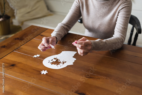 Cropped view of senior woman holding puzzle near table