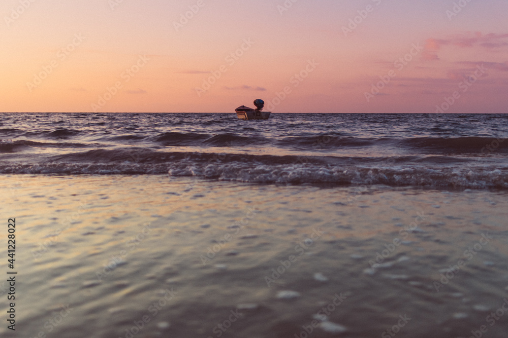 Small boat isolated on the sea on colorful sunset. Concept of lonely.