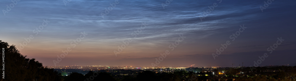 Beautiful panoramic view of very rare noctilucent clouds and stars shining through them seen in Dublin, Ireland on summer solstice of 2021 before midnight. Details of NLC. Night shining panorama