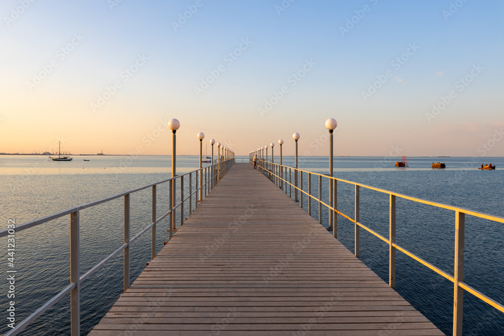 The wooden pier from the pedestrian path between a sheer cliff and the sea. Sunrise time, Caspian sea, Aktau, Kazakhstan.