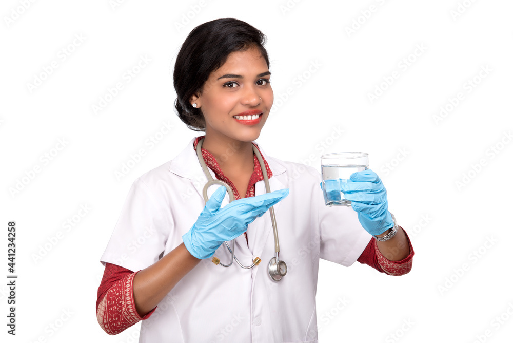 Healthy eating or lifestyle concept: Smiling female doctor holding a glass of clear fresh water Healthy eating or lifestyle concept: Smiling female doctor holding a glass of clear fresh water