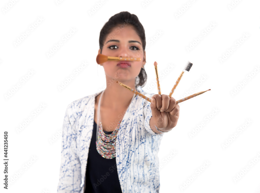 Beautiful young girl enjoying with makeup brushes isolated on white Beautiful young girl enjoying with makeup brushes isolated on white