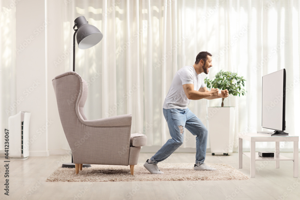 Guy at home watching a tv and gesturing happiness Guy at home watching a tv and gesturing happiness