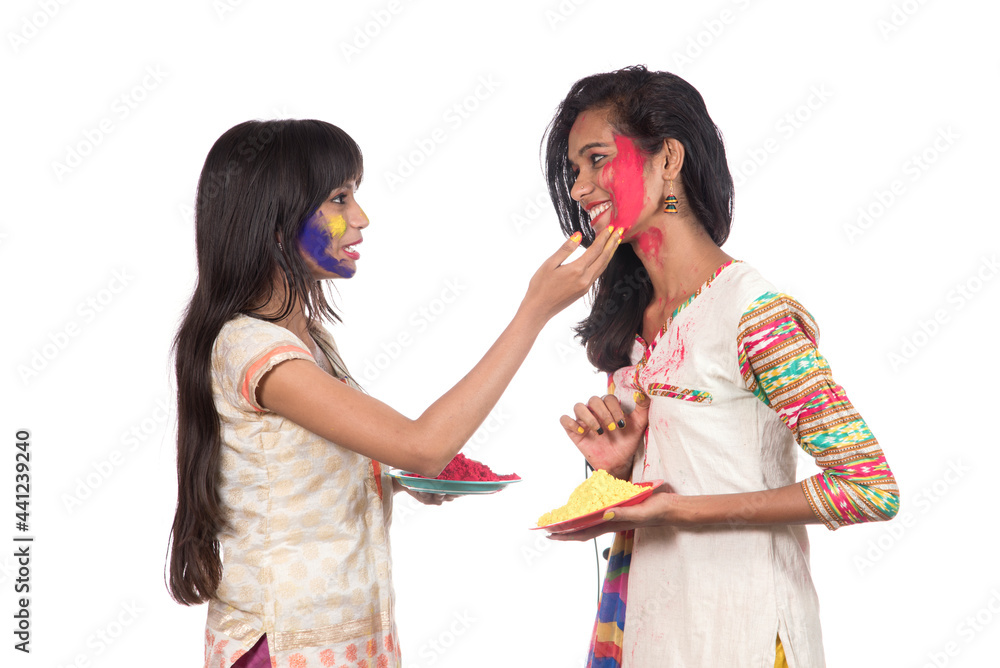 Happy young girls having fun with colorful powder at Holi festival of colors Happy young girls having fun with colorful powder at Holi festival of colors