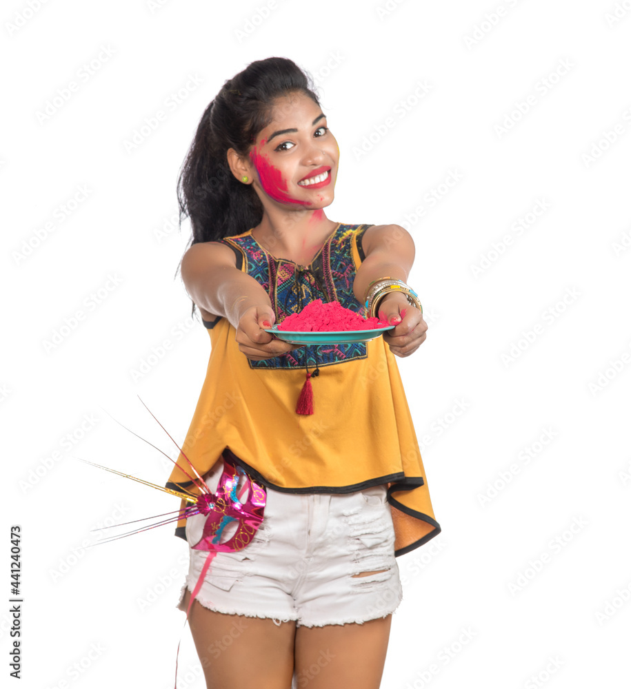 Beautiful young girl holding powdered color in plate with carnival mask on the occasion of Holi festival. Beautiful young girl holding powdered color in plate with carnival mask on the occasion of Holi festival.