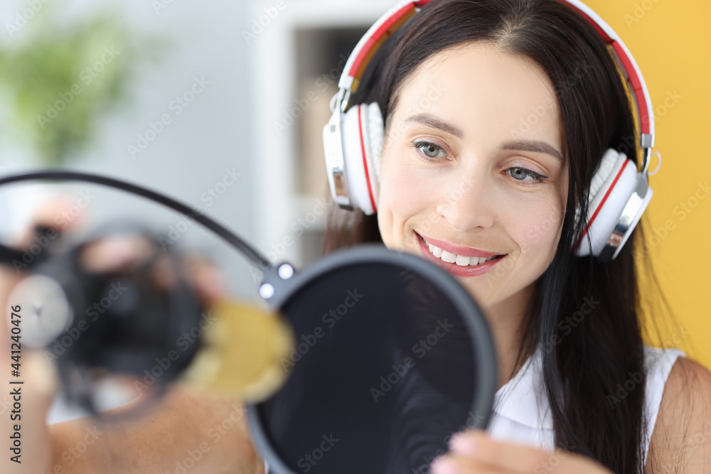 Portrait of young woman in headphones in front of microphone Portrait of young woman in headphones in front of microphone