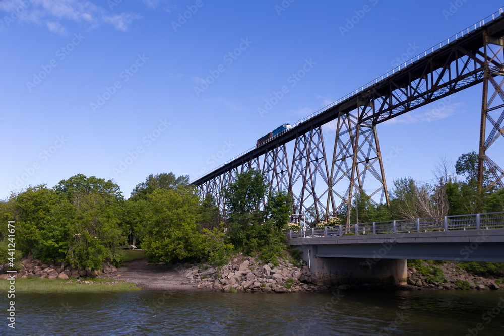 Locomotives on the 1908 railway trestle bridge over the valley of the Cap-Rouge River seen from the St. Lawrence River shore during a sunny summer morning, Quebec City, Quebec, Canada