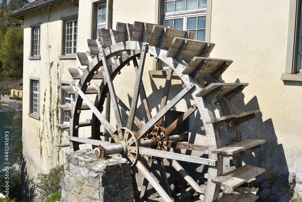 Old wooden water-wheel mill beside house at the Rhine Falls in Schaffhausen. Old wooden water-wheel mill beside house at the Rhine Falls in Schaffhausen.