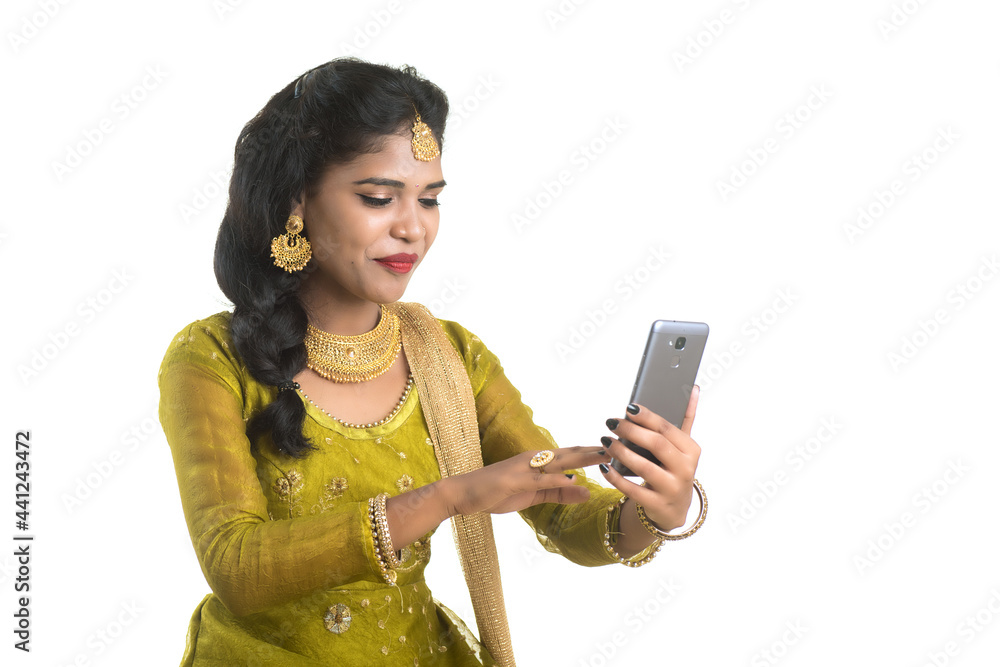Young Indian traditional girl using a mobile phone or smartphone isolated on a white background Young Indian traditional girl using a mobile phone or smartphone isolated on a white background