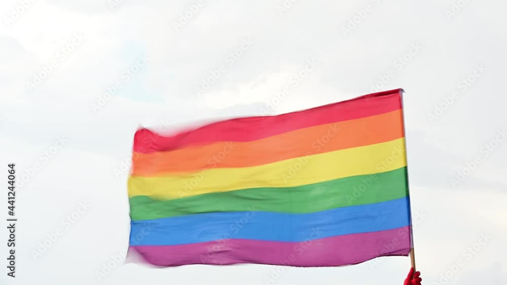 Hand holding multicolored flag blowing in the wind Hand holding multicolored flag blowing in the wind
